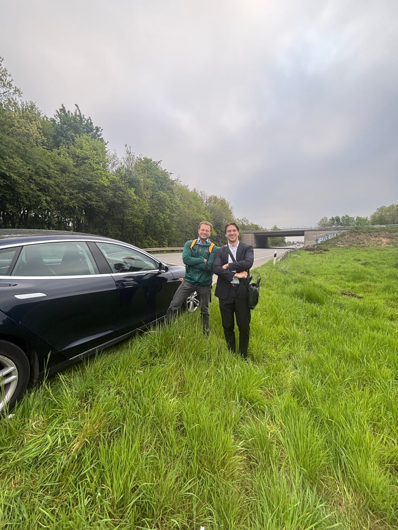 Together beside the car on the grassy verge of the motorway.